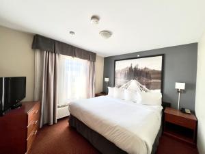 um quarto de hotel com uma cama grande e uma televisão em Super 8 by Wyndham Whitecourt em Whitecourt