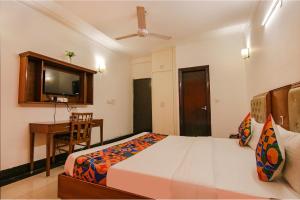 um quarto com uma cama, uma secretária e uma televisão em FabExpress JDM Residency em Gurgaon