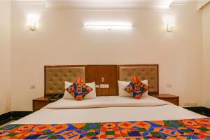 a bedroom with a large bed with colorful pillows at FabHotel JDM Residency in Gurgaon