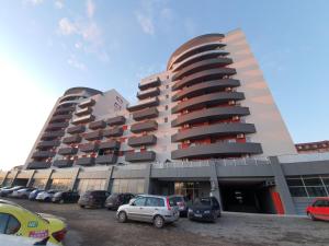 un grand bâtiment avec des voitures garées dans un parking dans l'établissement Luceafarul Property, à Oradea