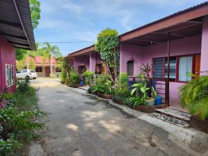 een roze huis met planten ervoor bij Gecko Guesthouse in Pantai Cenang