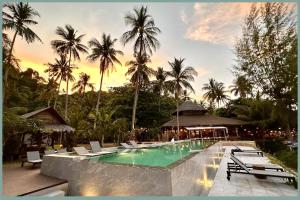 a swimming pool with lounge chairs and palm trees at Coco Cottage - SHA Plus in Ko Ngai