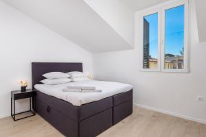 a bedroom with a bed with white sheets and a window at Apartment Pearl, Opatija center in Opatija