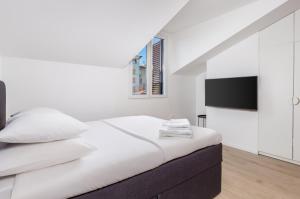 a white bedroom with a bed and a flat screen tv at Apartment Pearl, Opatija center in Opatija