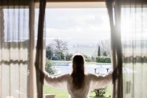 een vrouw kijkt uit een raam bij Adler Spa Resort Thermae in Bagno Vignoni