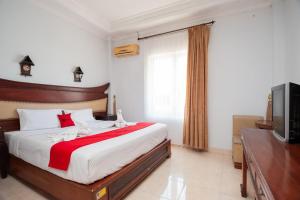 1 dormitorio con 1 cama grande y TV en RedDoorz Syariah near RS Yos Sudarso Padang en Padang