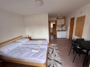 Cet appartement comprend une chambre avec un lit et une table ainsi qu'une cuisine. dans l'établissement Simple Apartman, à Siófok