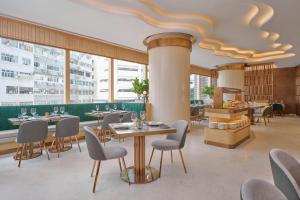 un restaurante con mesas, sillas y ventanas grandes en Crowne Plaza Hong Kong Causeway Bay, an IHG Hotel en Hong Kong