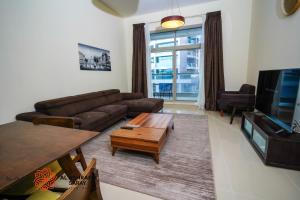 ein Wohnzimmer mit einem Sofa und einem Couchtisch in der Unterkunft Alashrafia Saray - Adorable 1BR in Sports City in Dubai