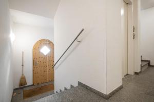 una scala in una parete bianca con una porta in legno di Cà Val Forno - Vacanze con stile a Maloja