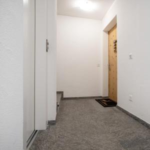 un corridoio vuoto con pareti bianche e una porta di Cà Val Forno - Vacanze con stile a Maloja