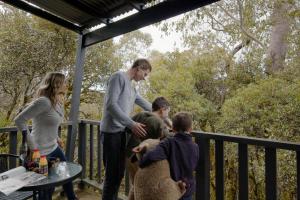 a group of people standing on a porch with a dog at CMWV Resort in Cradle Mountain