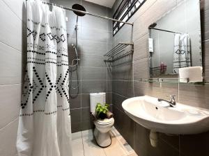 a bathroom with a sink and a toilet and a shower curtain at Desaru Utama Villa by Antlerzone in Bandar Penawar