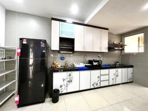 a kitchen with a black refrigerator and white cabinets at Desaru Utama Villa by Antlerzone in Bandar Penawar +57 photos