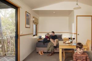 a man and woman sitting on a couch in a living room at Cradle Mountain Wilderness Village in Cradle Mountain