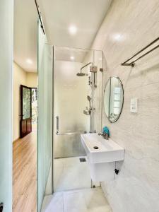 uma casa de banho com um lavatório, um chuveiro e um espelho. em Haven Vietnam em Quy Nhon