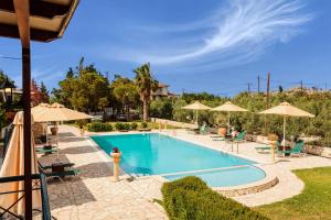 a swimming pool with chairs and umbrellas at Dukes Poolside Houses in Paralio Astros