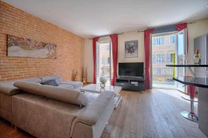 a living room with a couch and a brick wall at MODERNE 3 PIECES IDEALEMENT SITUE CENTRE DE CANNES l! A2B22 in Cannes