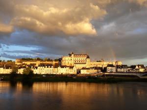 a city with a rainbow in the sky over the water at La Petite Lucette in Amboise