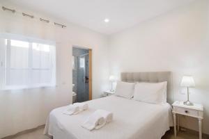 ein weißes Schlafzimmer mit 2 Handtüchern auf dem Bett in der Unterkunft Casa da Letinhas in Albufeira
