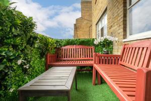 deux bancs rouges assis sur l'herbe devant un bâtiment dans l'établissement Luxury 3 Bedrooms Apartment in Central London, à Londres