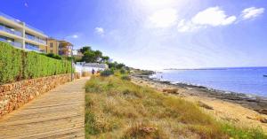 a boardwalk next to a beach next to a building at Colonia Sea Holiday in Colonia Sant Jordi