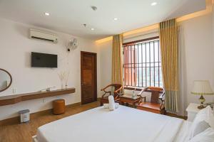 a hotel room with a bed and a tv at SeaColor Beachstay Danang Hotel by Haviland in Da Nang