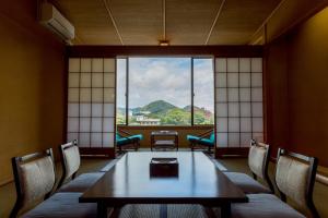 a room with a table and chairs and a window at New Hakkeien in Izunokuni