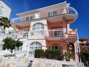 ein rosafarbenes Haus mit Balkon darüber in der Unterkunft Apartments Jakšić in Trogir