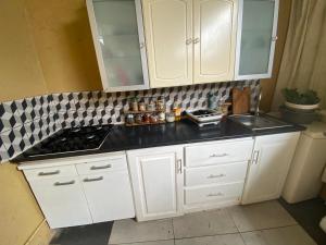 La cuisine est équipée de placards blancs, d'une cuisinière et d'un évier. dans l'établissement Casa Chiquinha, à Ribeira da Prata
