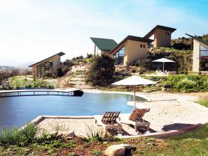 a house with a swimming pool with two chairs and an umbrella at Botë Farms Agriturismo in Sarandë