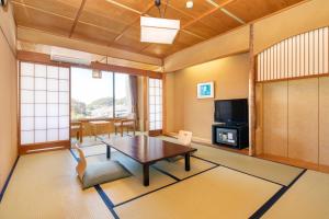 a living room with a table and a tv at New Hakkeien in Izunokuni