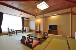 a living room with a table and a tv at New Hakkeien in Izunokuni