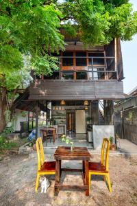 ein Haus mit einem Holztisch und 2 Stühlen in der Unterkunft Bunga Hostel in Pantai Cenang