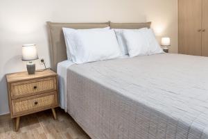 a bed with white sheets and pillows next to a night stand at Barbaras Apartments in Kato Daratso +50 photos