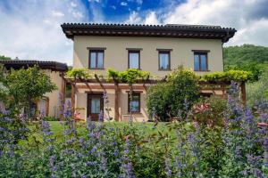 a house in the middle of a garden with purple flowers at Incantico "Eco Resort" in Assisi