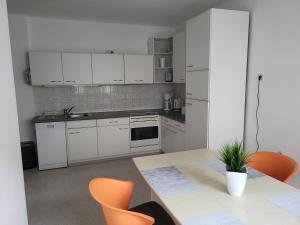 eine Küche mit weißen Schränken sowie einem Tisch und Stühlen in der Unterkunft Ferienwohnung Braunshardt in Weiterstadt