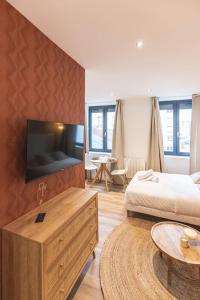 1 dormitorio con 1 cama y TV en la pared en Morphée - Résidence Hestia, en Saint-Étienne