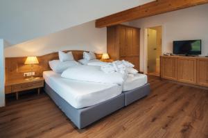 a bedroom with a large bed with white sheets and pillows at Hotel Garni Alpenruh-Micheluzzi in Serfaus