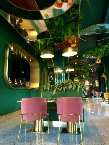 a restaurant with pink chairs and a green wall at Ego SPA in Birštonas