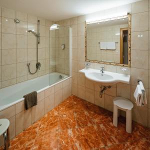 a bathroom with a sink and a tub and a mirror at Hotel Garni Alpenruh-Micheluzzi in Serfaus