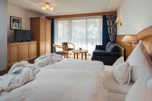a bedroom with a white bed and a living room at Hotel Garni Alpenruh-Micheluzzi in Serfaus