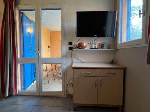 een kamer met een tv en een glazen schuifdeur bij Charmant appartement en résidence de vacances avec piscine in Argelès-sur-Mer