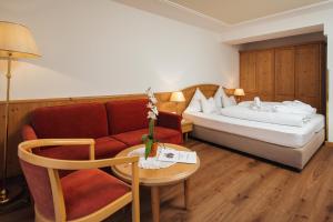 Habitación de hotel con cama, sofá y mesa en Hotel Garni Alpenruh-Micheluzzi, en Serfaus
