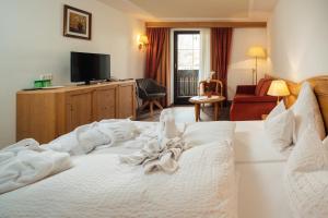 a hotel room with a white bed and a television at Hotel Garni Alpenruh-Micheluzzi in Serfaus