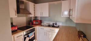 uma cozinha com armários brancos e um micro-ondas vermelho em Modern and spacious Swansea centre apartment em Swansea