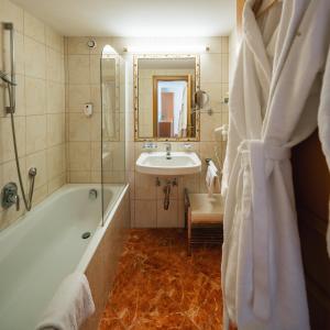 a bathroom with a bath tub and a sink at Hotel Garni Alpenruh-Micheluzzi in Serfaus