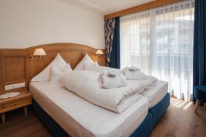 a bedroom with a large white bed with a window at Hotel Garni Alpenruh-Micheluzzi in Serfaus