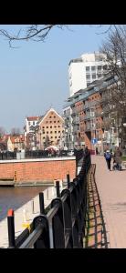 a row of black benches next to a river with buildings at Gdańska Marina- Śródmieście in Gdańsk