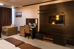Habitación de hotel con cama, escritorio y TV. en Hotel Dream en Sofía